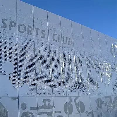 Exterior perforated metal wall panels where variable hole sizes form the words SPORTS CLUB and athlete figures