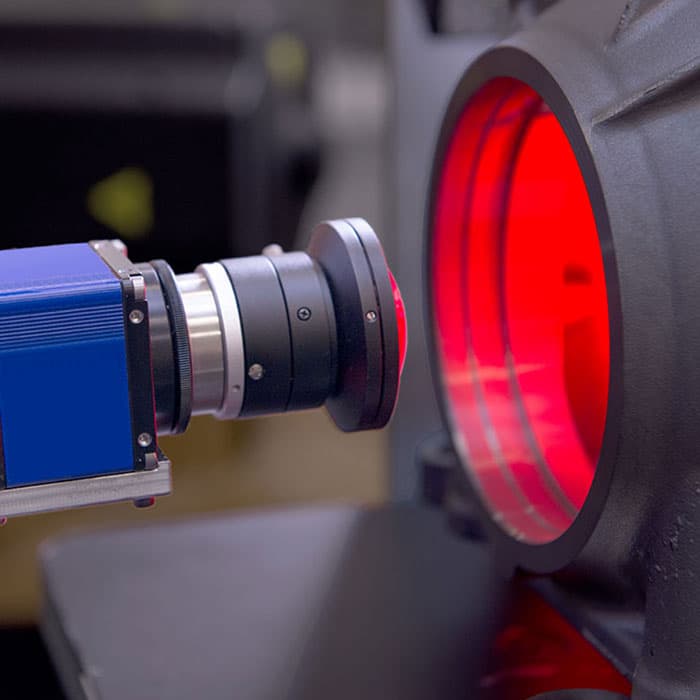 Red-coated lens on a laser cutting head, close up on the machine