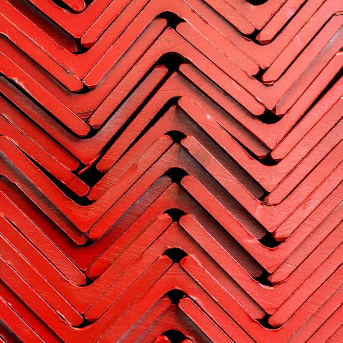 Red-primed steel angle sections stacked in a chevron pattern